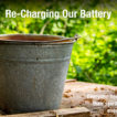 A bucket on a woodent table with writing over it, "Recharging Our Battery."