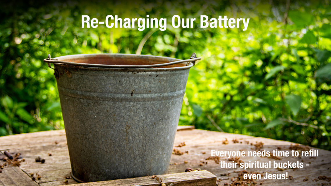 A bucket on a woodent table with writing over it, "Recharging Our Battery."