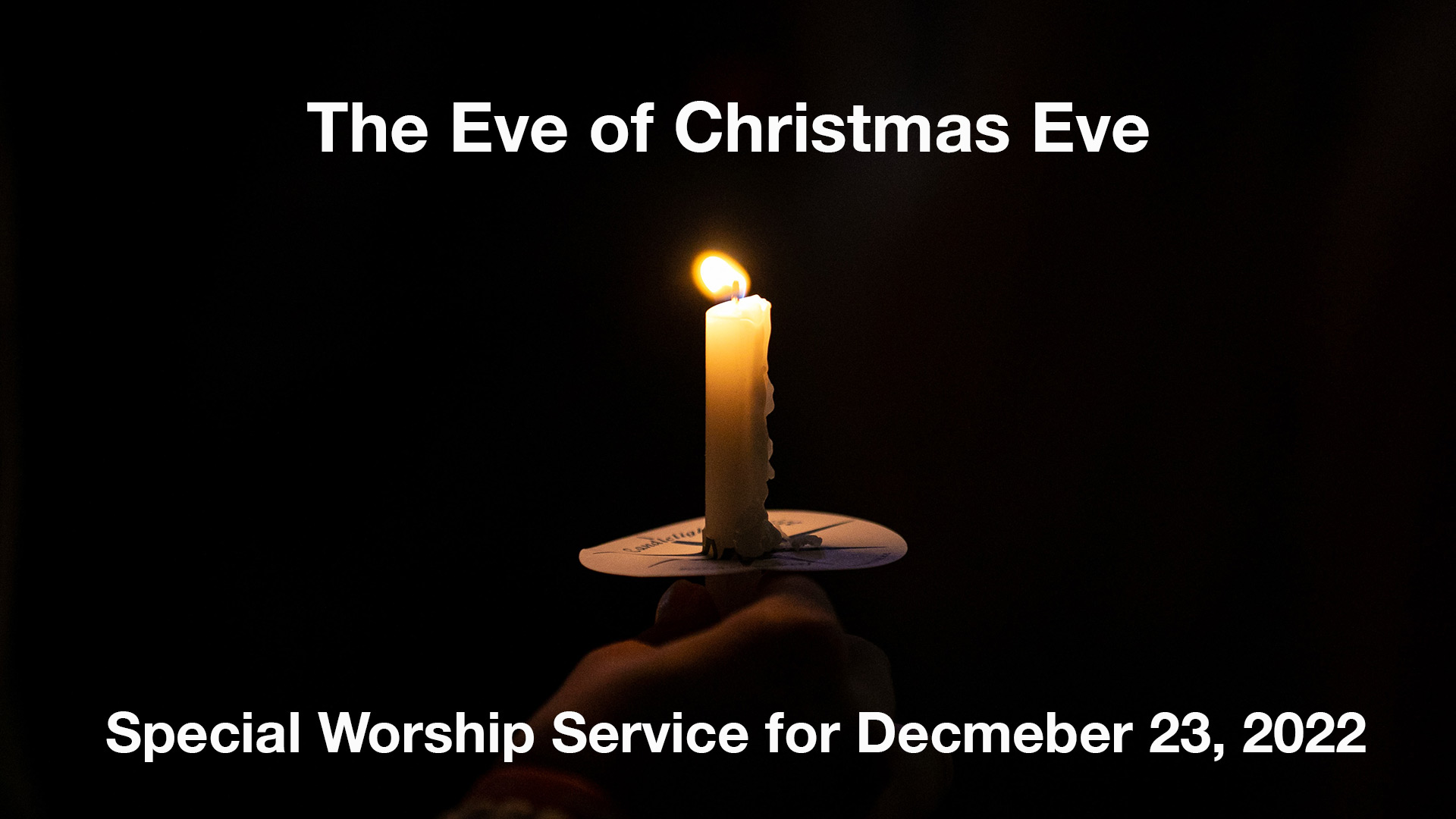 A hand holding a candle in the dark.